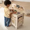 A young boy is playing with a wooden toy kitchen. Anteprima dell’immagine prodotto