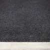 A close-up view of a dark gray carpet with a textured, melange appearance, resting on a light gray wooden floor. Produktbild-Vorschau