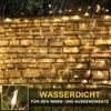 A string of warm white fairy lights draped over a stone wall during a rain shower. Náhled obrázku produktu