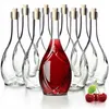 A group of clear glass bottles with cork stoppers, one of which is filled with red liquid. Three cherries are in the foreground. Voir les images du produit