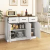 A white buffet cabinet with a brown top, featuring three drawers and two cabinet doors, is shown in a dining room setting. The cabinet is filled with various kitchen items and tableware. Podgląd zdjęcia produktu