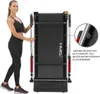 A woman stands next to a folded treadmill. Voir les images du produit