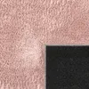 A close-up view of a pink rug, showing its texture and the black backing with a dotted pattern. Produktbild-Vorschau