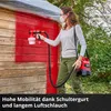 A woman is painting a wooden shed with a red paint sprayer. Produktbild-Vorschau