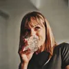 A woman is drinking from a glass of ice and liquid. Produktbild-Vorschau