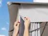 Hands adjusting the fabric of a gray gazebo. Produktbild-Vorschau
