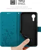 A hand is holding a teal phone case open, revealing the black TPU shell inside. The case has a floral and butterfly design on the inside flap. Náhled obrázku produktu