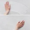 Two close-up shots of a hand touching a white surface, possibly demonstrating the texture or softness of a carpet. Produktbild-Vorschau