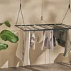 A ceiling-mounted clothes drying rack with laundry hanging on it, next to a large green plant. Produktbild-Vorschau