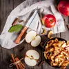 A rustic arrangement of apples, dried apple slices, and cinnamon sticks on a wooden surface. Anteprima dell’immagine prodotto