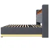 A side view of a gray upholstered bed frame with a slatted mattress support and a wooden headboard with shelves. Produktbild-Vorschau