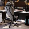 A gaming chair is set up at a desk with a computer and accessories in a modern room. Náhľad obrázku produktu