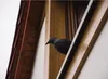A black bird is perched on a wooden beam, looking out from a window. Náhľad obrázku produktu