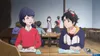 Two young people are sitting at a table in what appears to be a cafe or restaurant, looking at papers and talking. Produktbild-Vorschau