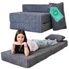 A woman is lying on a folded mattress that is part of a sofa bed. Voir les images du produit