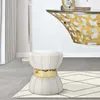 A cream and gold stool sits on a rug in front of a console table with a gold butterfly design. Produktbild-Vorschau