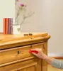 A hand is using a red tool to repair a wooden dresser drawer. Podgląd zdjęcia produktu