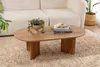 A wooden coffee table with a plant and books on it, placed on a rug in front of a sofa. Voir les images du produit