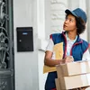 A delivery person stands outside a building with packages. Náhled obrázku produktu