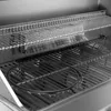 Close-up view of the interior of a gas grill, showing the cooking grates, warming rack, and a drip pan. Produktbild-Vorschau