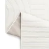 A close-up view of a folded white rug with a subtle striped pattern. Anteprima dell’immagine prodotto
