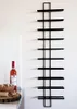 A black metal wine rack mounted on a white wall, with a bottle of rosé wine and a bowl of corks on a countertop to the left. Náhled obrázku produktu