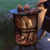 A person is grilling meat and vegetables on a BonFeu fire pit in an outdoor setting at dusk. Produktbild-Vorschau