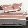 A neatly made bed with striped bedding and pillows. Produktbild-Vorschau