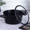 A black pot with a glass lid is placed on a wooden surface, with a plant in the background. Podgląd zdjęcia produktu
