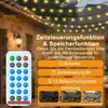 A remote control for solar string lights is shown in the foreground, with the string lights hanging in the background over a building. Náhled obrázku produktu