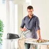 A man is ironing clothes on an ironing board in a well-lit room. Voir les images du produit
