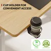 A close-up view of a desk with a cup holder attached to the edge, holding a disposable coffee cup. The desk has a light wood grain finish. There are also certification logos at the bottom right. Voir les images du produit