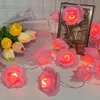 A string of LED rose lights and tulips are arranged on a white surface, with a framed picture in the background. Produktbild-Vorschau