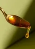 A close-up of a spoon holding honey, with a drop of honey falling. Produktbild-Vorschau