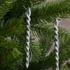 Two silver glittery icicle ornaments hang from a green Christmas tree. Anteprima dell’immagine prodotto