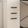 A close-up view of a white cabinet with three drawers, each featuring a black handle. Náhled obrázku produktu