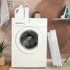 A laundry room scene with a washing machine, laundry detergent, a plant, and an ironing board with an iron. Produktbild-Vorschau