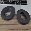 Two black oval-shaped ear pads are placed on a wooden surface in front of a laptop keyboard. Anteprima dell’immagine prodotto