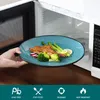 A hand is placing a plate of food into a microwave. Voir les images du produit