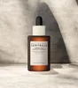 A bottle of Skin1004 Madagascar Centella Probio-Cica Intensive Ampoule is displayed against a textured gray and white background with dramatic shadows. Produktbild-Vorschau
