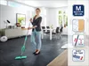 A woman is cleaning a floor with a mop in a modern living room. Produktbild-Vorschau