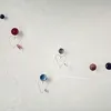 Several decorative wire heart ornaments with small colored balls attached, arranged on a white wall. Produktbild-Vorschau