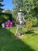 A garden scene with decorative metal flowers and a figure holding a planter. Produktbild-Vorschau