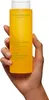 A hand holding a yellow bottle of Clarins Tonic Bath & Shower Concentrate. Anteprima dell’immagine prodotto