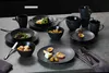 A table setting with black dinnerware, food, and fruit. Náhled obrázku produktu