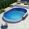 An oval swimming pool is set up on a paved patio, surrounded by wooden decking and landscaping. Produktbild-Vorschau