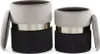 Two cylindrical ottomans are shown side-by-side against a white background. The ottomans have a two-tone design, with a gray velvet top and a black base, separated by a silver band. One ottoman's lid is slightly ajar. Produktbild-Vorschau