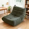 A green sofa is placed in a room with a wooden desk and a bookshelf. Produktbild-Vorschau