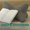 A gray pillow and an open book on a wooden surface. Produktbild-Vorschau
