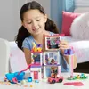 A young girl is playing with a Barbie Mega Construx toy set, which appears to be a multi-story villa with accessories. Podgląd zdjęcia produktu